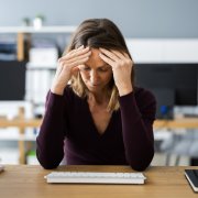 Woman holding head at her desk